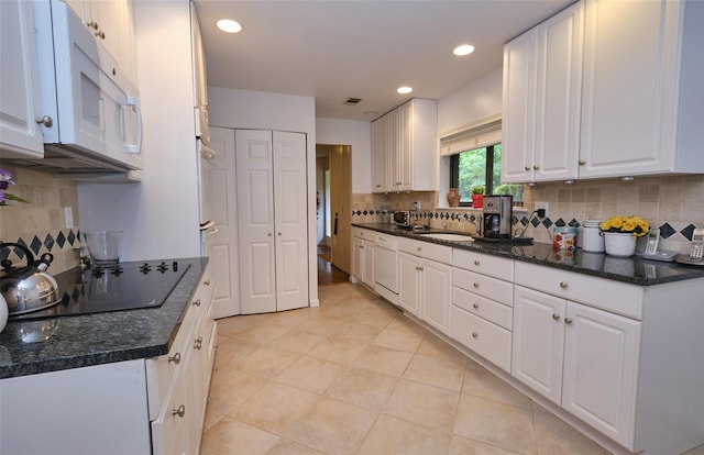 kitchen with tasteful backsplash, white cabinetry, sink, and white appliances