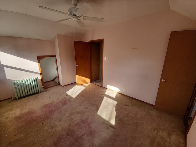 spare room with radiator, ceiling fan, light colored carpet, and lofted ceiling