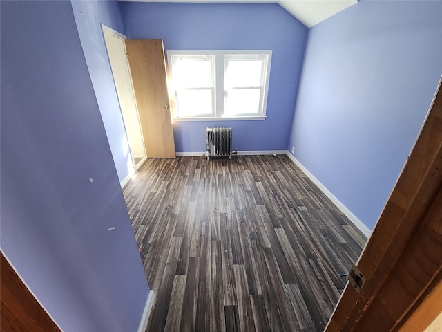 spare room with dark hardwood / wood-style flooring, radiator heating unit, and lofted ceiling