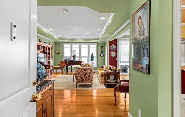 interior space featuring a raised ceiling, wood-type flooring, and crown molding