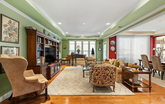 living room with light wood-type flooring, crown molding, and a raised ceiling