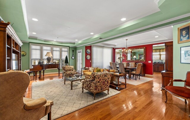 living room with a chandelier, crown molding, light hardwood / wood-style flooring, and a raised ceiling