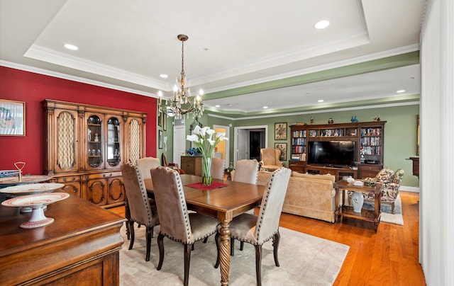 dining space with a tray ceiling, ornamental molding, and light hardwood / wood-style floors