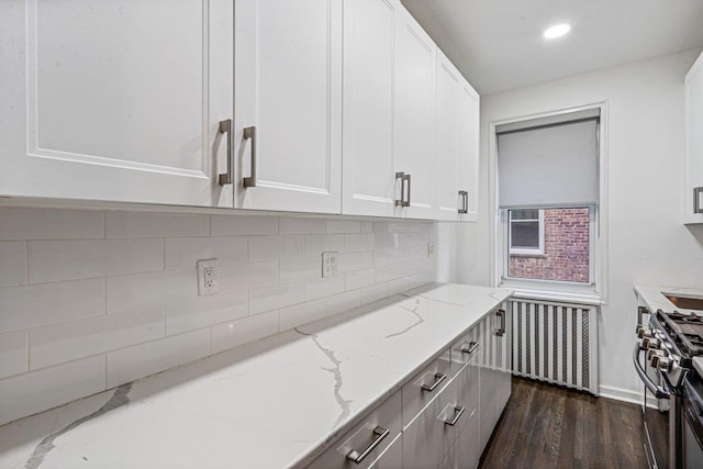 kitchen with radiator, white cabinetry, dark wood-type flooring, light stone counters, and high end stove