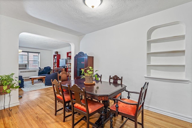 dining area with light hardwood / wood-style floors, built in features, and a textured ceiling