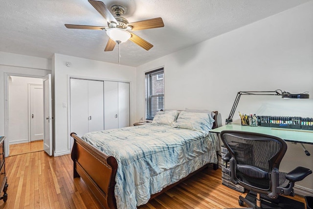 bedroom with hardwood / wood-style floors, a textured ceiling, a closet, and ceiling fan