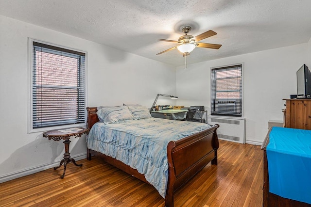 bedroom featuring ceiling fan, dark hardwood / wood-style flooring, radiator heating unit, and a textured ceiling