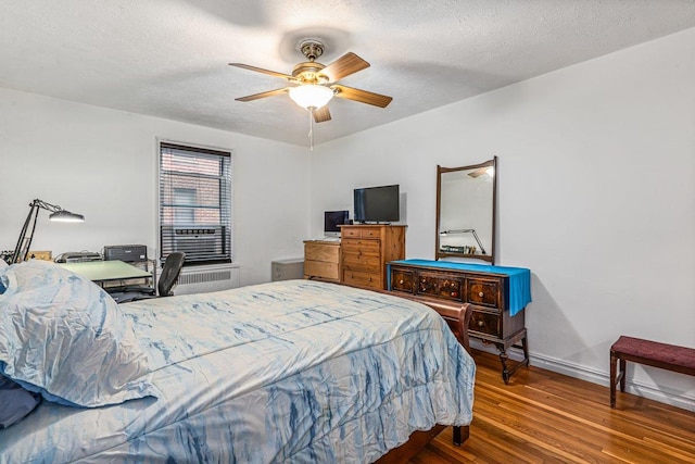 bedroom with a textured ceiling, hardwood / wood-style flooring, and ceiling fan