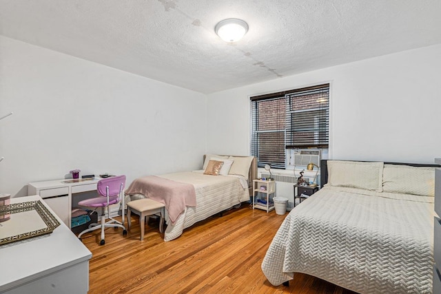 bedroom featuring hardwood / wood-style floors, a textured ceiling, and radiator