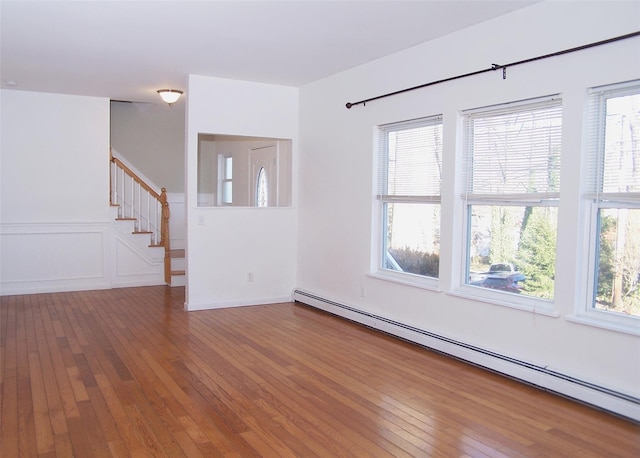 empty room with hardwood / wood-style flooring, a baseboard radiator, and plenty of natural light