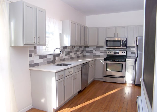 kitchen with sink, tasteful backsplash, dark hardwood / wood-style floors, baseboard heating, and appliances with stainless steel finishes