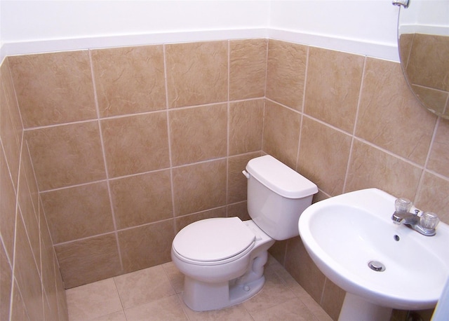 bathroom with sink, toilet, tile walls, and tile patterned floors