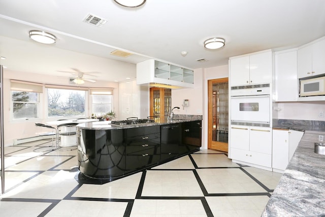 kitchen with white appliances, ceiling fan, dark stone counters, white cabinets, and light tile patterned flooring