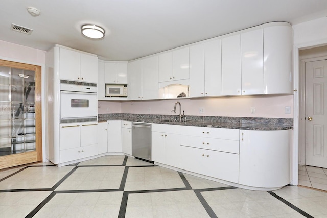 kitchen featuring white appliances, sink, light tile patterned floors, and white cabinetry