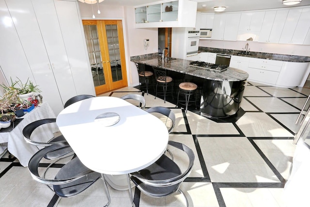 kitchen featuring white appliances, white cabinets, light tile patterned flooring, and french doors