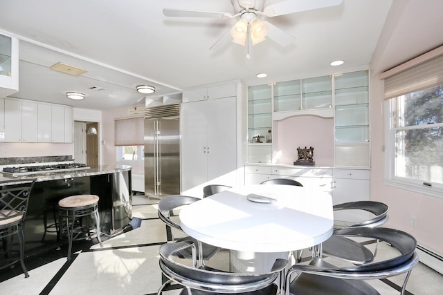 dining area featuring ceiling fan, baseboard heating, a wealth of natural light, and light tile patterned floors