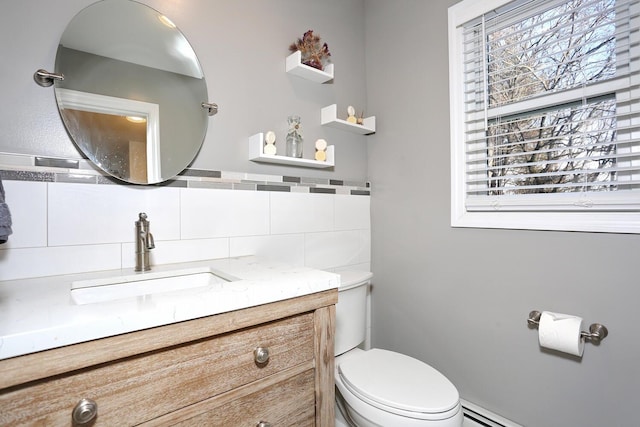 bathroom with toilet, vanity, a baseboard heating unit, and backsplash