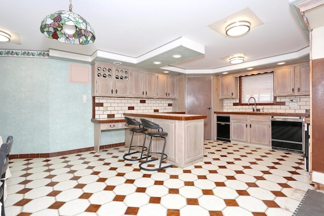 kitchen featuring a breakfast bar area, tile counters, pendant lighting, sink, and black dishwasher