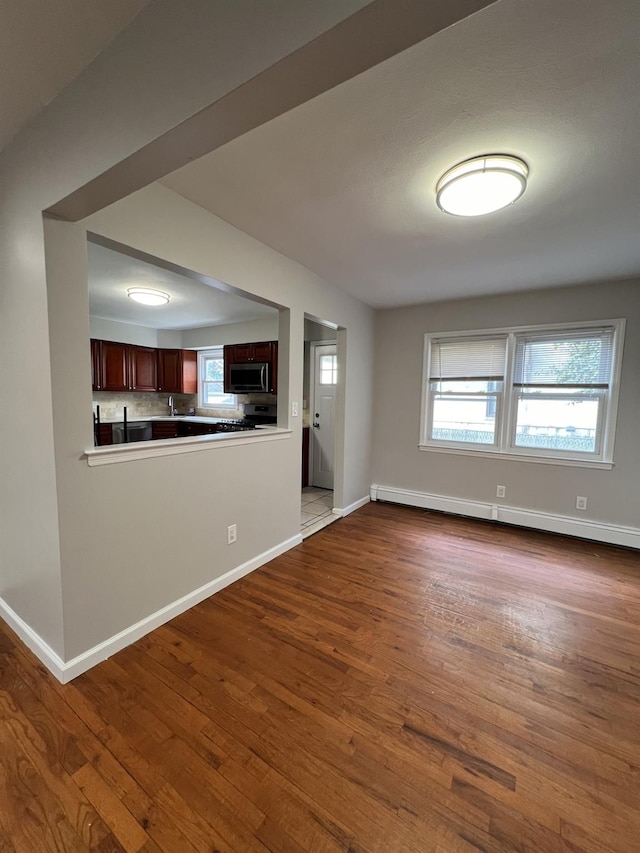 unfurnished living room with hardwood / wood-style flooring and baseboard heating