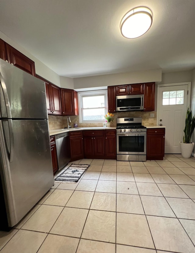 kitchen with tasteful backsplash, sink, light tile patterned floors, and stainless steel appliances