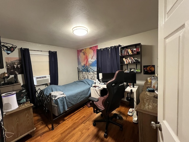 bedroom with hardwood / wood-style floors, cooling unit, and a textured ceiling