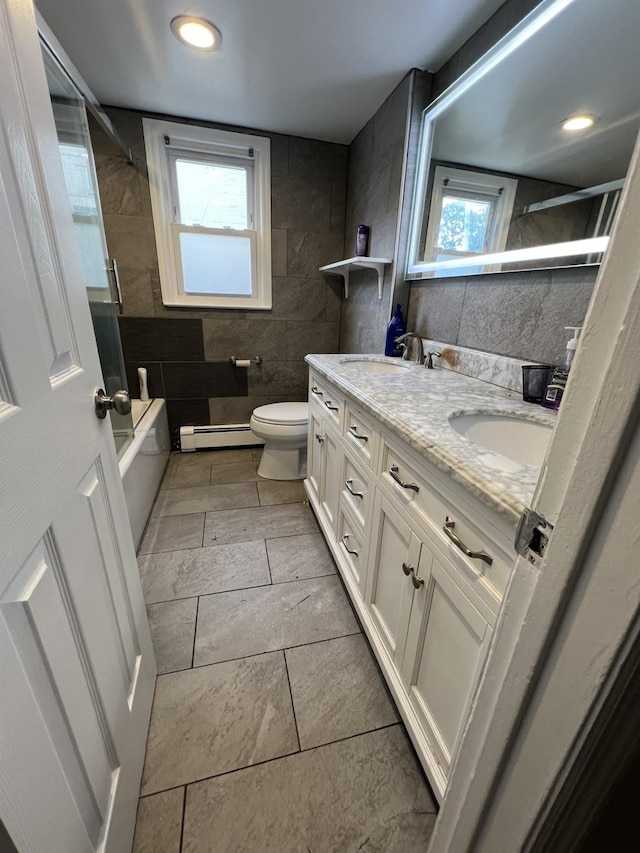 bathroom featuring a wealth of natural light, vanity, tile walls, and a baseboard heating unit