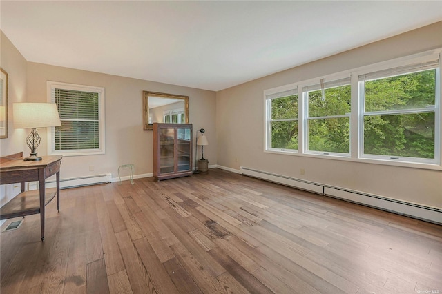 empty room with light wood-type flooring and a baseboard heating unit