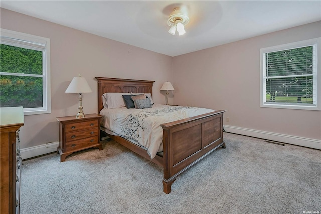 bedroom featuring ceiling fan, light carpet, and a baseboard heating unit