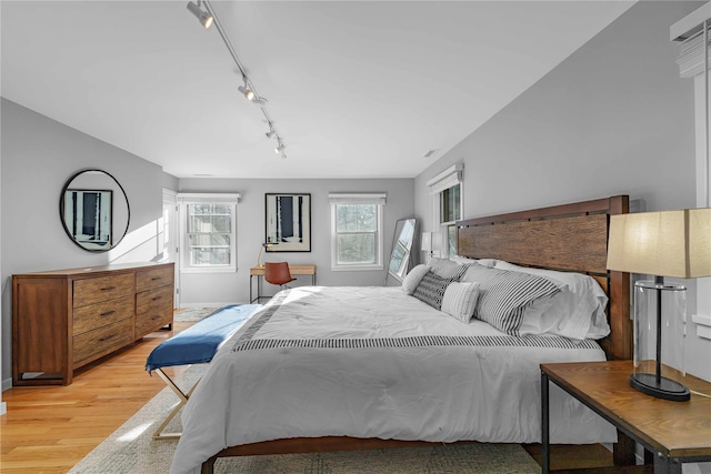 bedroom with rail lighting and light hardwood / wood-style floors