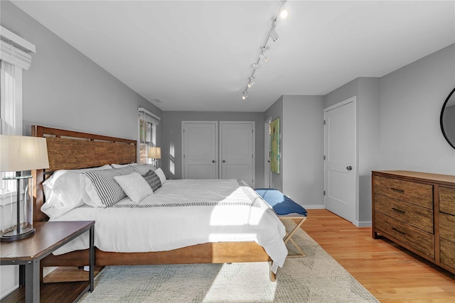 bedroom with light hardwood / wood-style floors and track lighting