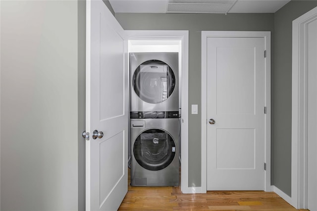 washroom featuring stacked washing maching and dryer and light hardwood / wood-style floors