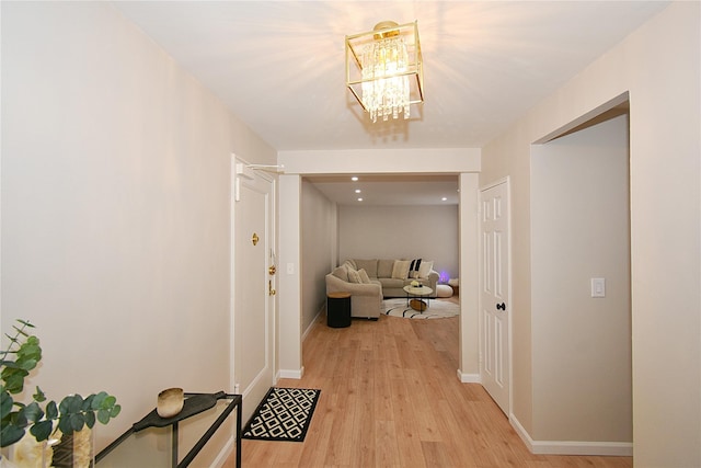 corridor with a notable chandelier and light wood-type flooring