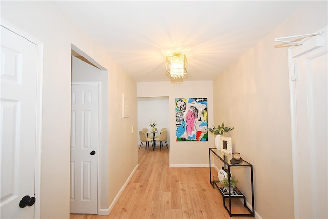 hallway featuring an inviting chandelier and light hardwood / wood-style flooring