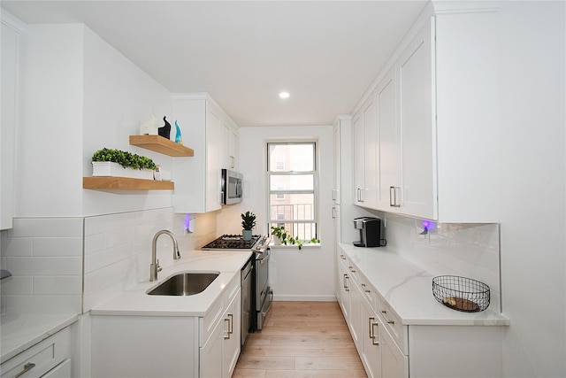 kitchen with sink, decorative backsplash, stainless steel appliances, and white cabinets