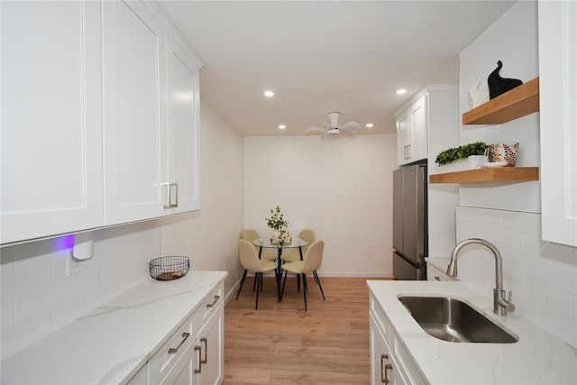 kitchen featuring white cabinetry, sink, and light stone countertops