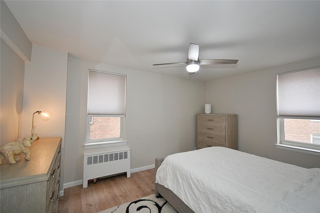 bedroom featuring multiple windows, radiator, light hardwood / wood-style floors, and ceiling fan