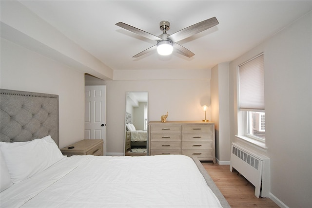 bedroom with ceiling fan, radiator heating unit, and light wood-type flooring