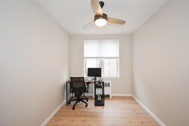 office area featuring radiator heating unit, light hardwood / wood-style floors, and ceiling fan