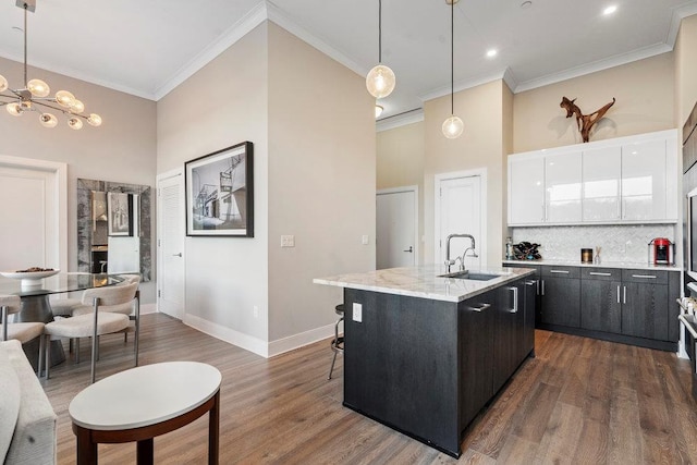 kitchen with dark hardwood / wood-style floors, a center island with sink, sink, white cabinetry, and hanging light fixtures