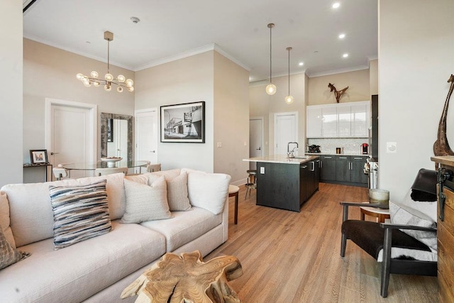 living room with sink, crown molding, a chandelier, and light hardwood / wood-style flooring