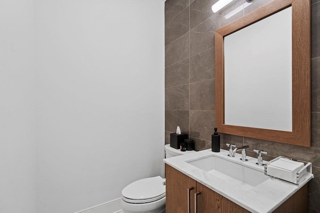 bathroom featuring toilet, tile walls, and vanity