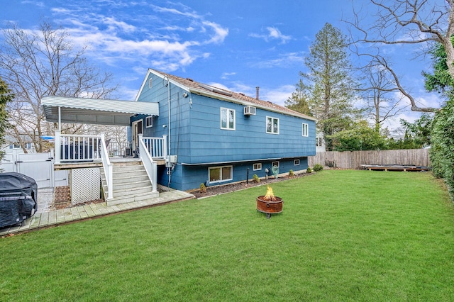 rear view of property featuring a wall mounted AC, an outdoor fire pit, a lawn, and a wooden deck