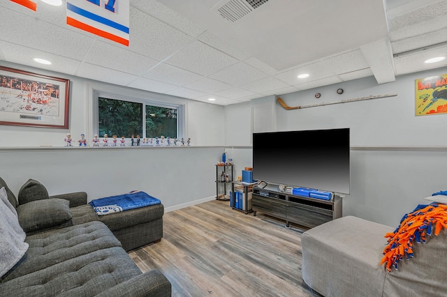 living room with a drop ceiling and light wood-type flooring