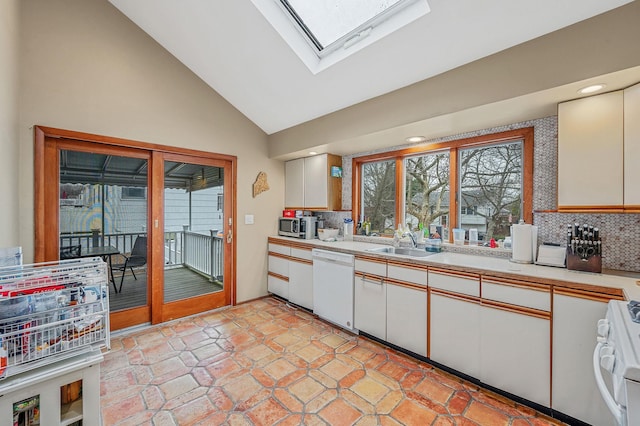 kitchen with backsplash, a skylight, white cabinetry, and white appliances