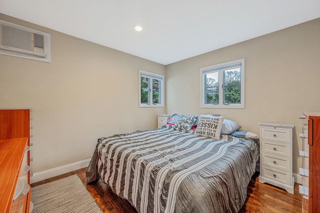 bedroom with an AC wall unit and dark hardwood / wood-style floors