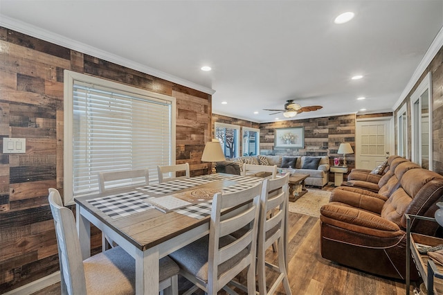 dining space featuring ceiling fan, wooden walls, ornamental molding, and hardwood / wood-style flooring