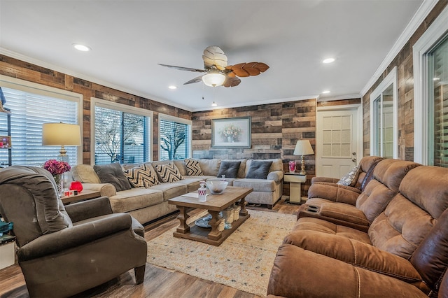 living room with ceiling fan, ornamental molding, light hardwood / wood-style flooring, and wooden walls