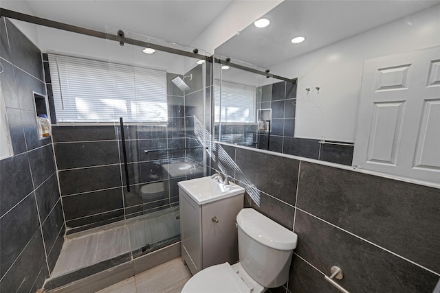 bathroom featuring toilet, a shower with door, vanity, and tile walls