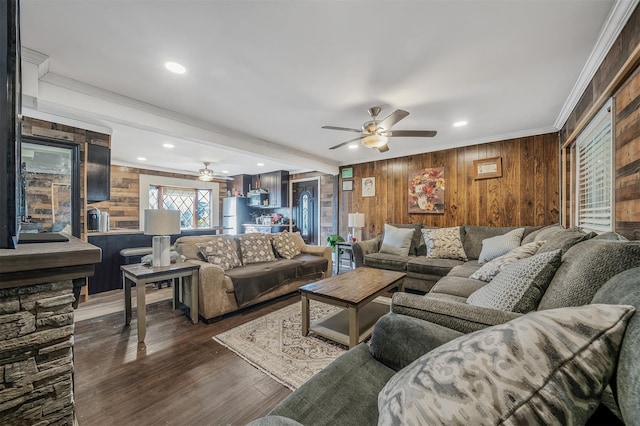 living room featuring dark wood-type flooring, ceiling fan, ornamental molding, and wooden walls