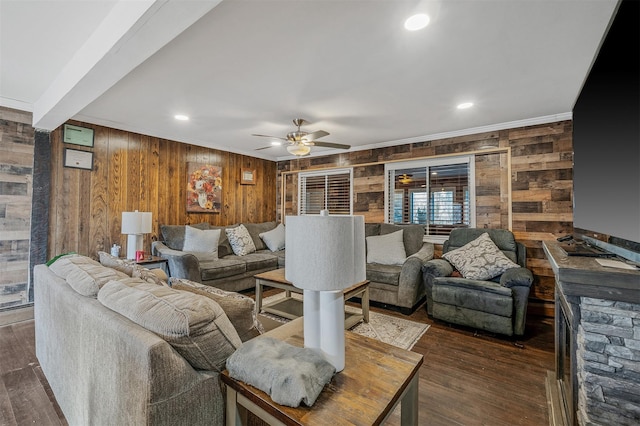 living room with ceiling fan, dark wood-type flooring, wooden walls, and ornamental molding